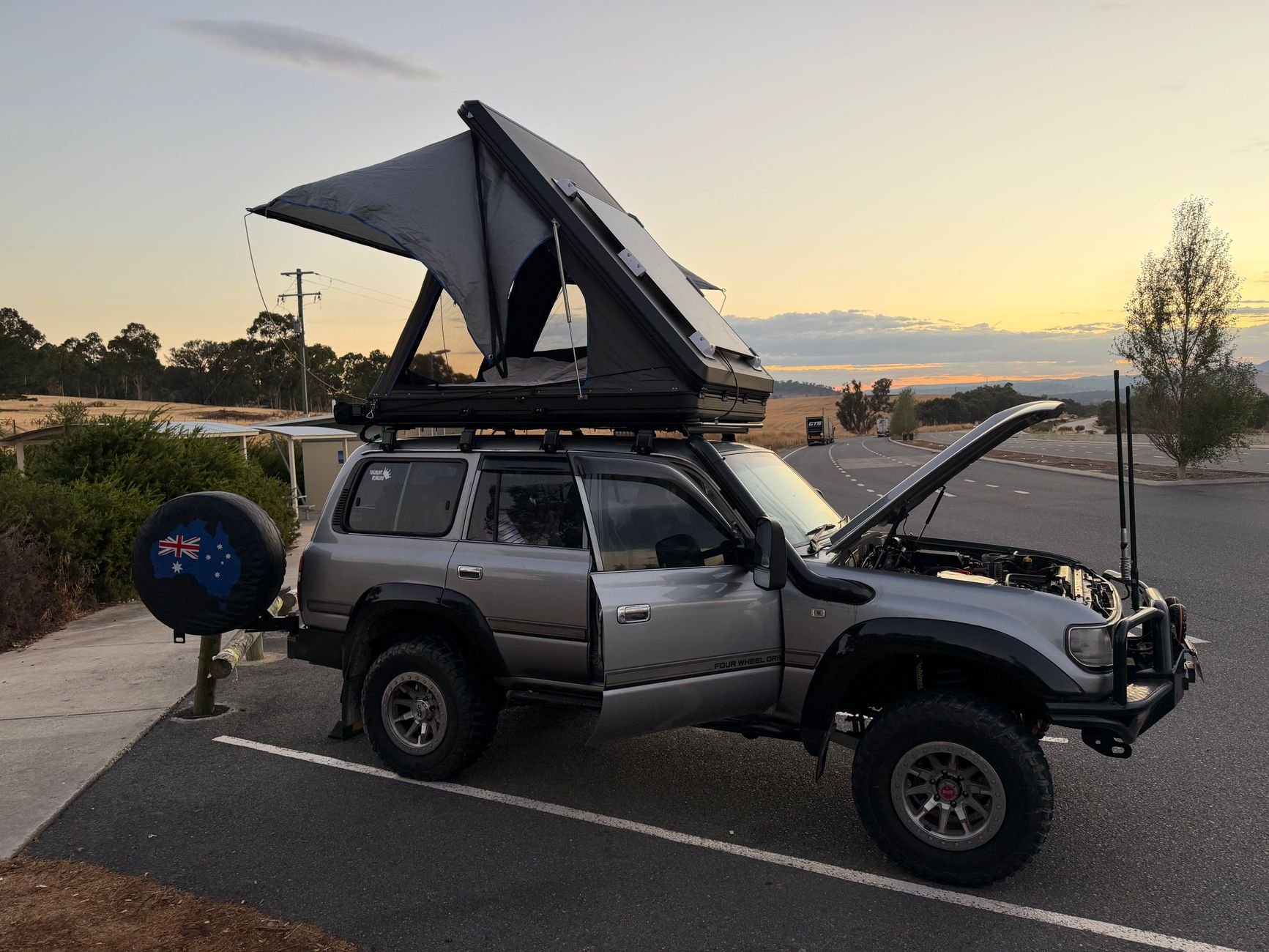SUV with rooftop tent at sunset roadside